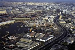 Image du Maroc Professionnelle de  Le Boulevard côtier (Les Almohades) qui serpente entre le port et la ville a été gagné sur la mer comme tous les terres-pleins à sa gauche , dont l'étendue est telle que seule une vue aérienne a pu saisir. En haut à droite c'est le quartier d'affaire et l'avenue des F. A. R. La darse portugaise a été séparé en deux pour être transformé en bassin d'armement et cale de radoub. Et au premier plan en bas à droite la plus ancienne mosquée de Casablanca Jamaa Ould El Hamra, Octobre 1989. (Photo / Abdeljalil Bounhar) 